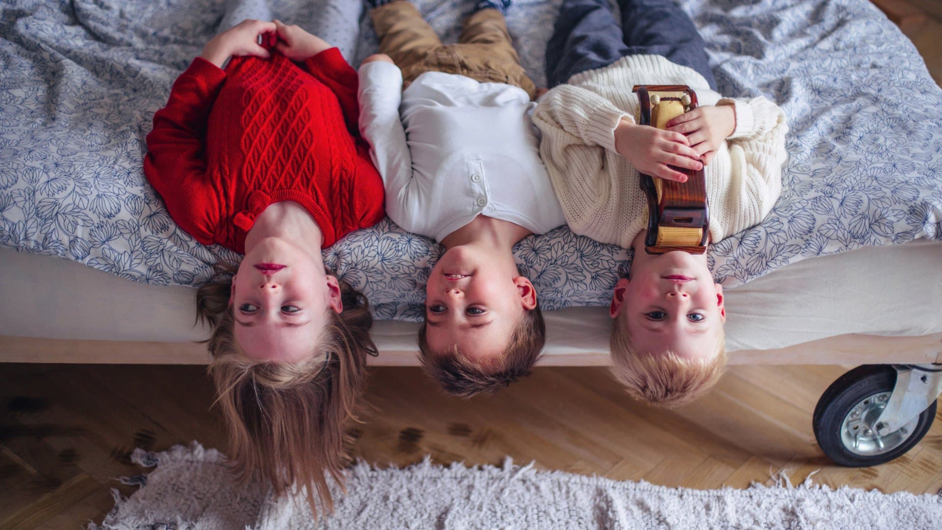 Three happy children lying on a bed together